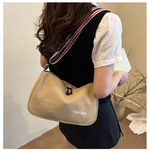 Détail du sac bandoulière en toile kaki avec large sangle tricolore et logo