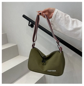Détail du sac demi-lune en nylon vert armée avec bandoulière large rayée stylée