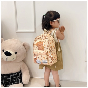 Détail d'un sac à dos enfant beige avec motifs Capybara porté par un jeune enfant