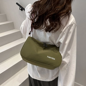 Army green nylon crossbody bag with striped strap shown on model's shoulder