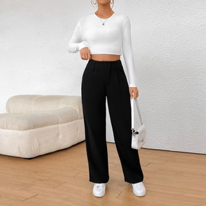 Détail du pantalon noir à jambe large taille haute et d'un haut court en maille blanc