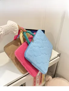Detailed shot of quilted laptop bags in khaki, pink, and blue with soft cloud texture