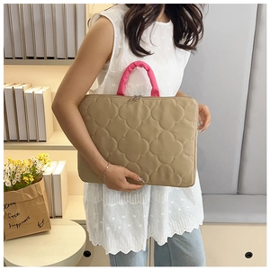 Close-up of khaki quilted laptop bag with pink handle and four-leaf clover pattern