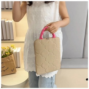 Close-up of beige quilted laptop bag with clover pattern and pink woven handles