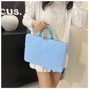 Detail of light blue laptop bag featuring floral quilted texture and sturdy handles