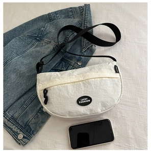 Detail of white nylon crescent bag with Lucky Fashion logo on textured background