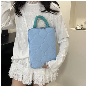 Close-up of a light blue quilted 11-inch iPad sleeve with turquoise pleated handles