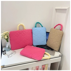 Detailed view of quilted floral laptop bags with contrast handles and metal zippers