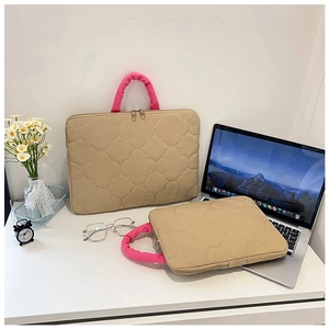 Detail of khaki quilted laptop bag with clover texture, pink handles and metal zippers