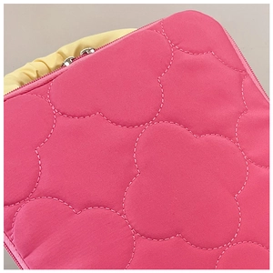 Macro detail of rose pink quilted fabric bag with yellow pleated handle and pink zipper
