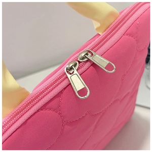 Detail of pink quilted laptop sleeve with dual metal zippers and yellow handles