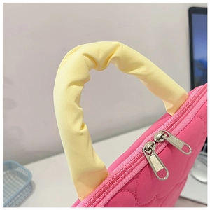 Detail of pink quilted laptop bag with heart texture, yellow handle and dual zippers