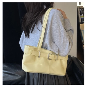 Detail of light yellow glossy leather shoulder bag with silver buckle and belt decoration