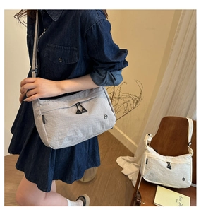 Détail d'un sac bandoulière léger en nylon gris clair avec étiquette latérale minimaliste