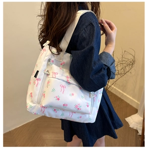 Detail of white tote bag featuring pink floral prints and ribbon bow patterns in daily use
