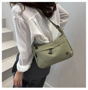 Detail of sage green nylon crossbody bag with adjustable strap and metal zippers