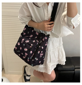 Detail of floral bow print nylon tote with functional zipper pockets and adjustable strap