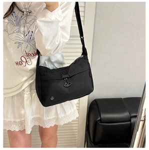 Détail du sac bandoulière en nylon noir avec double fermeture éclair et logo en métal