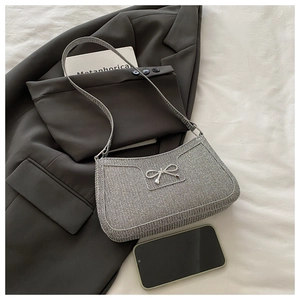 Dettaglio della borsa hobo tessuta argento con fiocco metallico e tracolla elegante