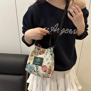 Floral print canvas bucket bag with cross-body strap shown on model for casual college style