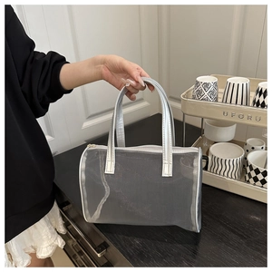 Détail d'un sac cabas en maille noire avec poignées argentées et fermeture éclair