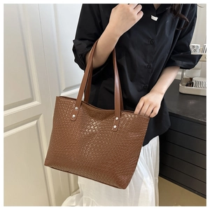 Detailed view of brown woven tote bag with smooth leather handles and silver metal rivets