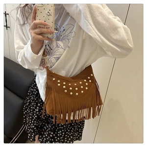 Mirror selfie showing the brown suede saddle bag with rivets and fringes worn as a crossbody