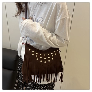 Macro detail of retro suede shoulder bag featuring long tassels and gold rivet studs