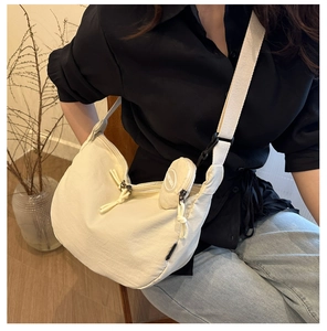 Detalle de bolso medialuna de lona blanco hueso con monedero y tirador de cremallera tejido