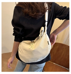 Off-white crescent nylon tote bag with small round pouch shown on a model's shoulder