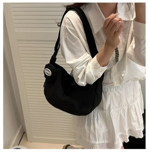Detail of nylon crescent bag with wide shoulder strap and circular coin purse attachment