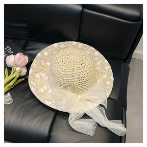 Detail of beige woven straw hat with white floral embroidery, pearls and mesh bow