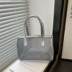 Gray mesh makeup bag with silver handles and gold zipper on a white book display