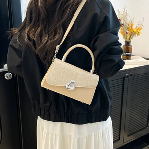 Chic beige V-shaped shoulder bag with glitter panel and heart lock worn by a model