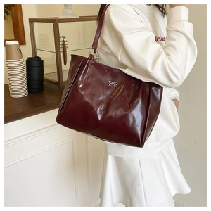 Gros plan sur un grand sac cabas rouge en cuir brillant avec un nœud argenté élégant