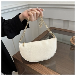 Detailed view of white pebbled leather texture and gold chain on crescent bag