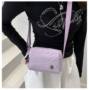 Detail of light purple nylon crossbody bag featuring wide strap and metallic M logo