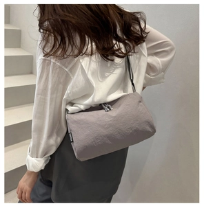 Détail du sac bandoulière gris avec fermeture à cordon et texture nylon gaufré