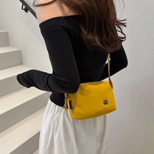Fashionable bright yellow crossbody square bag for women on minimalist white stairs