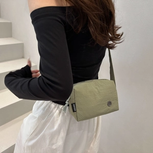 Sac bandoulière minimaliste en nylon vert avec bandoulière large et détail logo rond