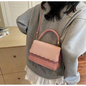 Detail of pink PU leather crossbody bag featuring textured woven flap and handle