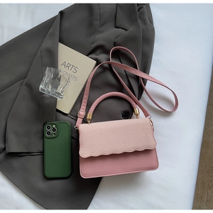 Detail of pink crossbody bag featuring woven flap and sleek gold metal clasp hardware