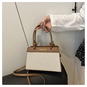 Detail of a brown faux leather and beige canvas tote bag with knot handle accents