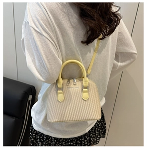 Detail showing the woven texture and fashion logo on this beige shell crossbody bag