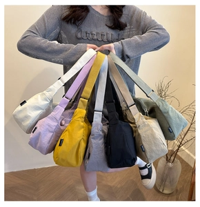 Detail view of colorful nylon crescent crossbody bags held by model in multiple shades