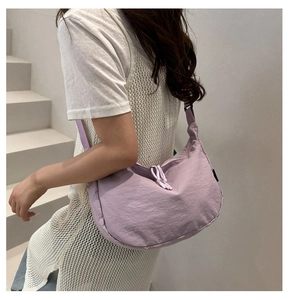 Side view of lavender purple nylon crescent crossbody bag with adjustable strap worn by model