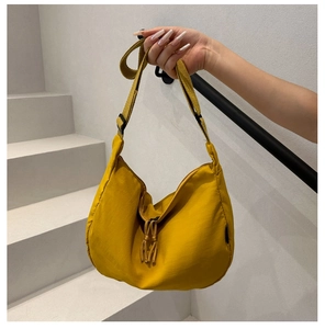 Detail of a bright yellow crescent nylon bag with adjustable strap and knot tassel detail