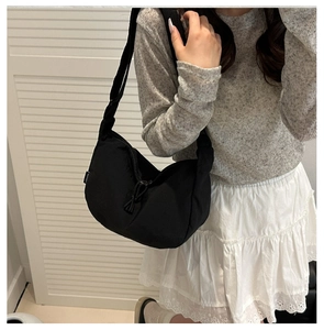 Detail of black nylon crescent bag with adjustable strap on a female model