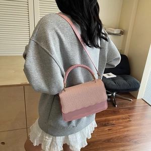 Pink crossbody bag with woven texture flap and smooth leather finish in a modern scene