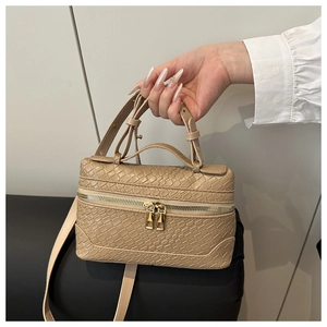Macro detail of beige faux crocodile texture and gold dual zipper on the tote bag